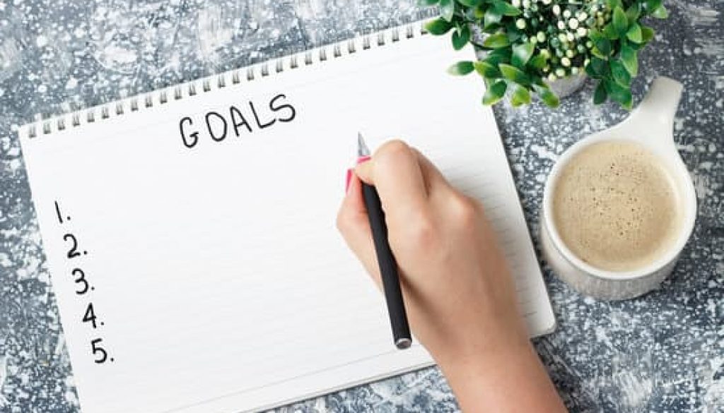 Female hand writes goals in a notebook, planning concept